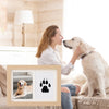 A woman gently touches the nose of a light-colored dog while posing for a DIY pet footprint memorial frame.