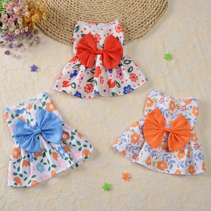 Une robe d'été colorée à motif floral et nœud orange, présentée sur un fond clair.