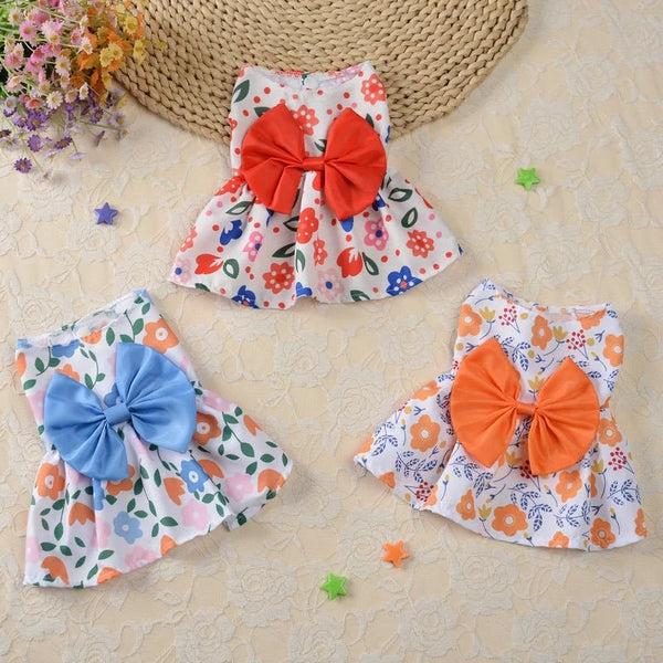 A colorful summer dress featuring a floral print and an orange bow, displayed on a light background.