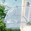 Clear plastic external bird bath designed for cages and parakeets, hanging near foliage.
