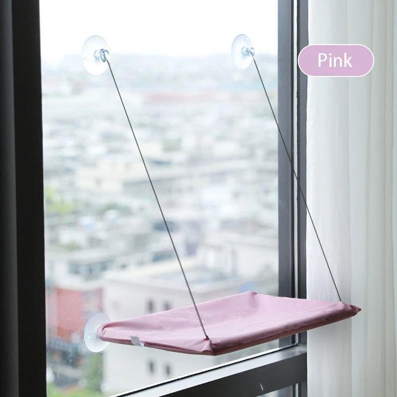 Pinkes Fenster-Hängebett für Katzen, aufgehängt an einem Fenster mit Stadtblick