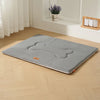 A gray waterproof dog bed mat with a bone shape and cushioned support placed on a light wooden floor.