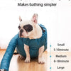 A white dog is sitting inside a blue foldable drying bag on a wooden floor.