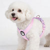 A fluffy white dog wearing a pink breathable no-pull harness with reflective strips.