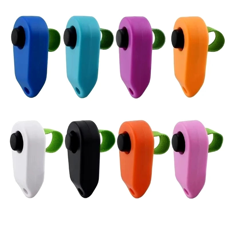 A set of colorful pet training clickers in blue, teal, purple, orange, black, and white plastic designs.