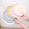 A hand is holding a stack of colorful silicone pet feeding mats for dogs and cats.