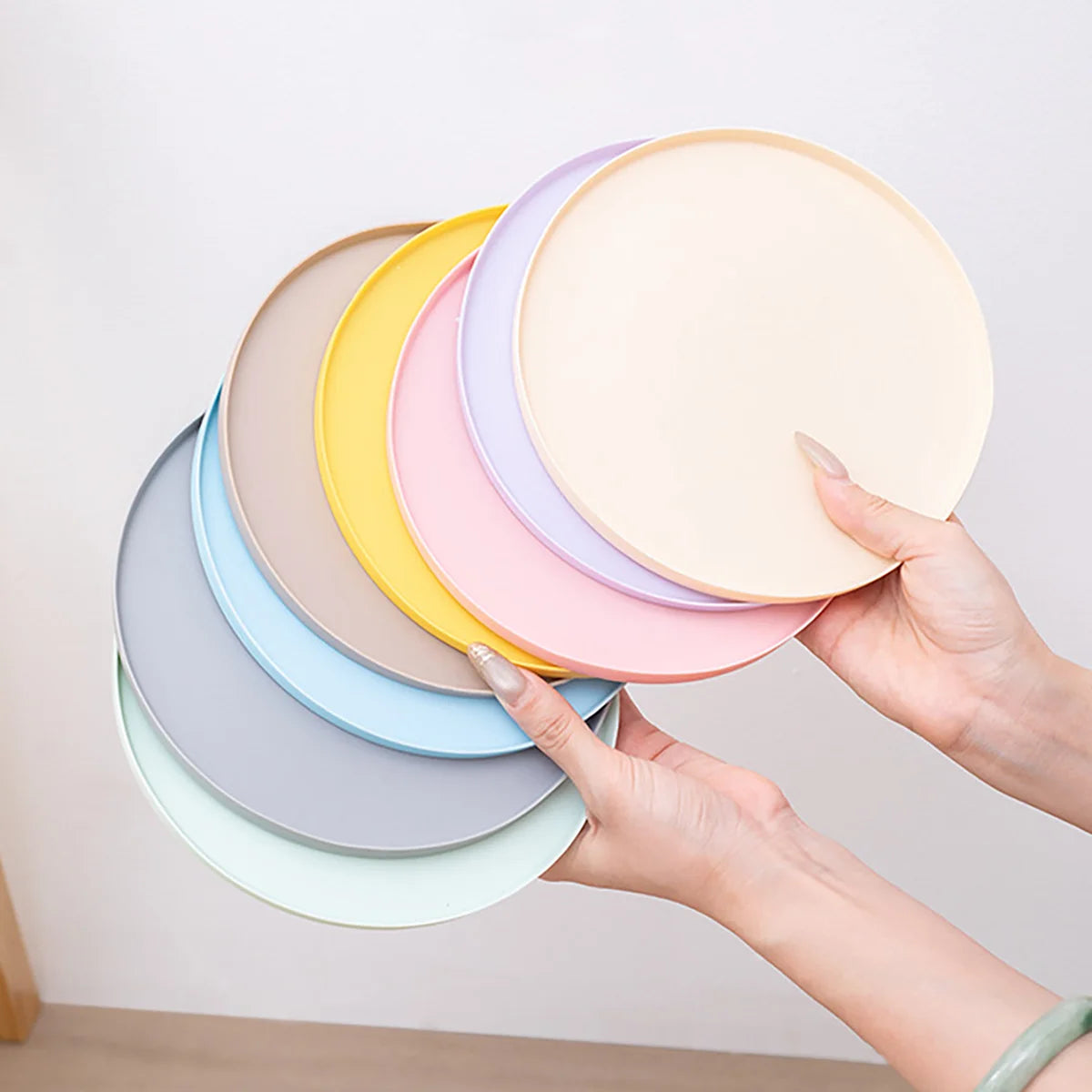 A hand is holding a stack of colorful silicone pet feeding mats for dogs and cats.
