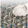 A white cat paw rests on a honeycomb litter mat filled with small, light-colored pellets and blue accents.