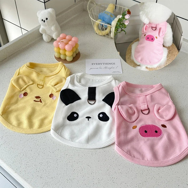 A collection of waffle knit pet vests for dogs and cats in yellow, white, and pink colors displayed on a countertop.