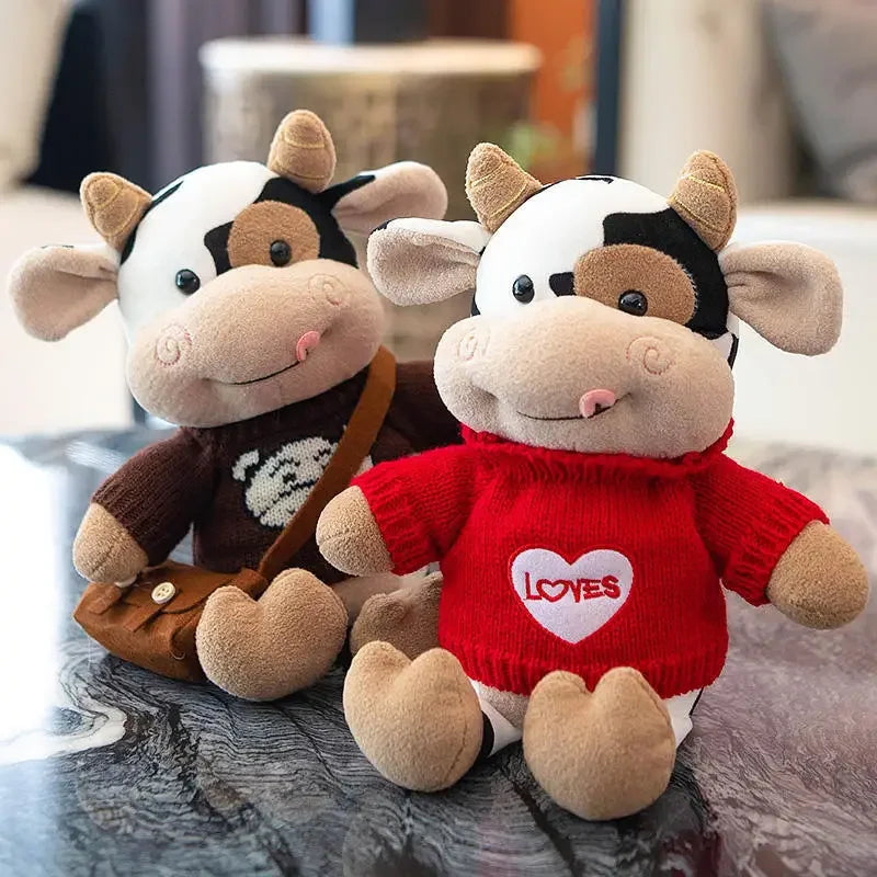 A pair of adorable soft cow plush toys with black and white markings sitting on a dark surface.
