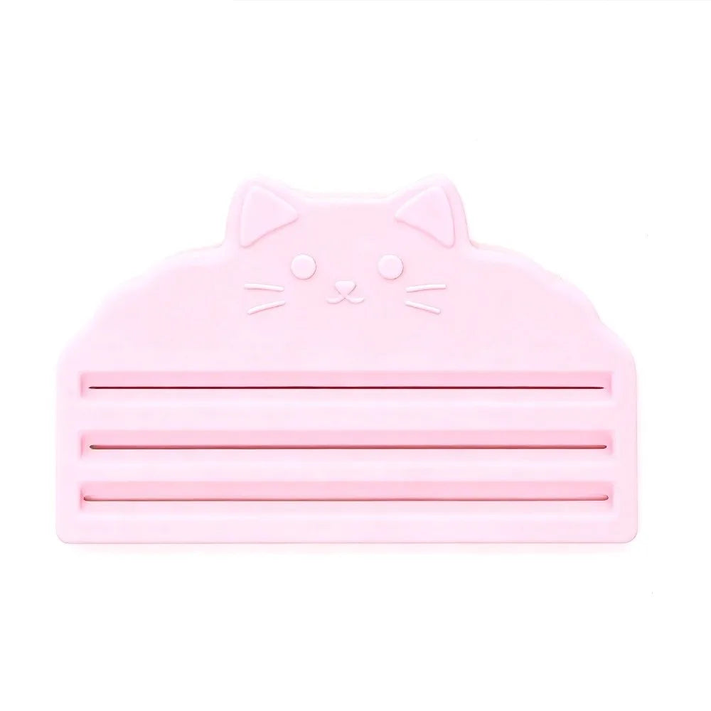 A pink reusable cat food pouch scraper shaped like a cat's head.