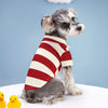 A gray and white dog wearing a red and white striped polo shirt sitting on a white surface.