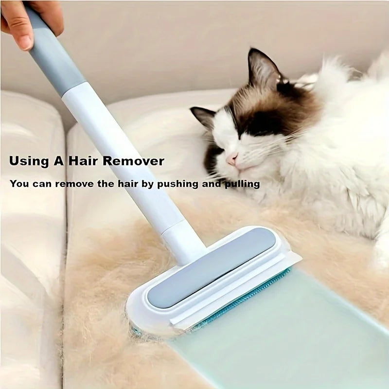 A hand is using a light blue reusable dog hair brush to remove hair from a white cat's fur on a beige surface.