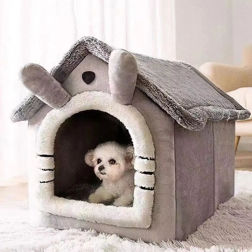 A gray dog house pet bed with a felt roof and an arched entrance, featuring a small white puppy inside.