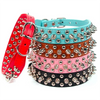 A stack of five adjustable leather spiked dog collars in various colors including red pink teal brown and black.