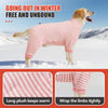 Un perro dorado vistiendo un traje de invierno de polar a rayas rosa y blanco al aire libre en condiciones de nieve.