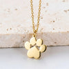 A gold-colored stainless steel cat paw pendant necklace resting on a white surface.