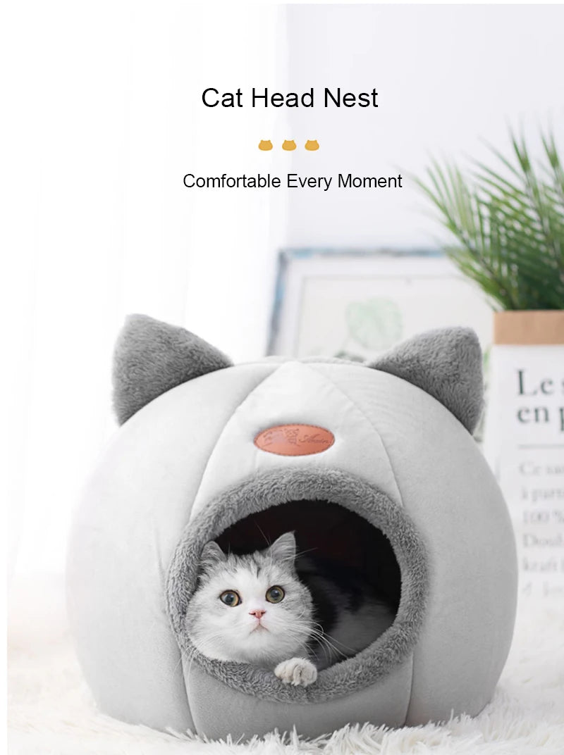 A gray plush cat head nest with an entrance, featuring a small kitten inside.