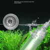 A clear glass aquarium gravel cleaner and water changer with a siphon pump is shown in a natural, sandy environment.