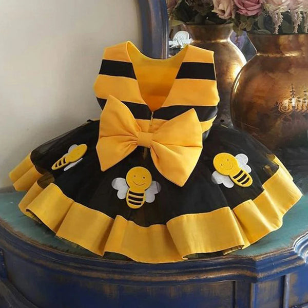 Robe tutu d'abeille, jaune avec rayures noires et grand nœud, sur une surface en bois.