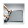 A hand is holding a gray silicone dog pee pad holder for indoor training.