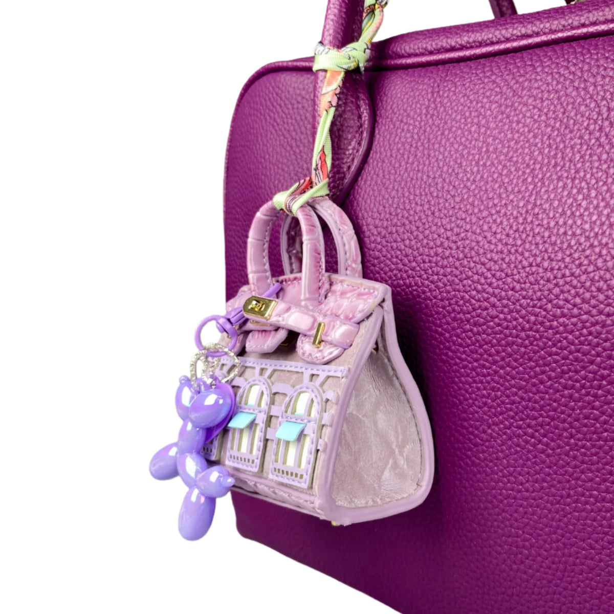 A handcrafted mini house-shaped bag in light purple with a puppy keychain charm hanging from the strap.