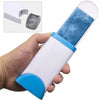 A hand holds a white lint remover brush with a blue grip and a blue fuzzy lint-removing pad.