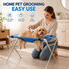 A woman is grooming a dog using an adjustable pet grooming hammock stand for easy at-home pet grooming.