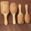 Three natural bamboo air cushion hair brushes with massage bristles displayed on a brown surface.