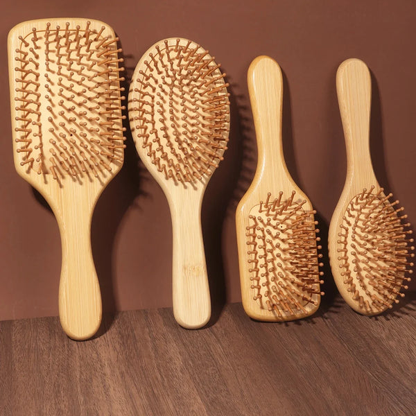 Three natural bamboo air cushion hair brushes with massage bristles displayed on a brown surface.