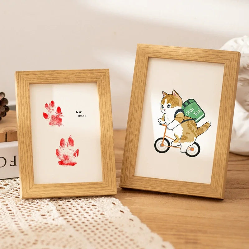 A wooden photo frame displays a paw print design, featuring a cat and a dog riding a green bicycle.