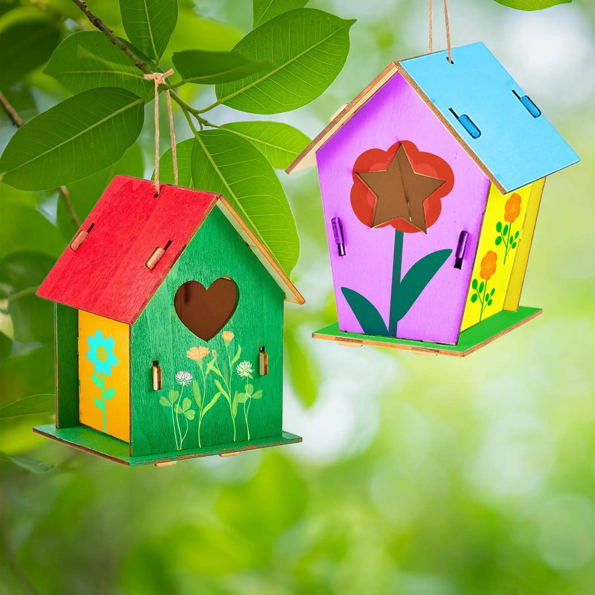 Handmade wooden bird houses in various colors and designs suspended from a green leaf.