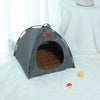A gray foldable pet tent for cats and small animals resting on a white fluffy surface.