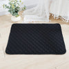 Black quilted reusable washable pet training mat placed on a light wooden floor next to a white lace fabric.