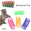 Eine Sammlung farbenfroher Springspielzeuge für Katzen, darunter grüne, blaue und orange Spiralen, neben einem grauen Kätzche
