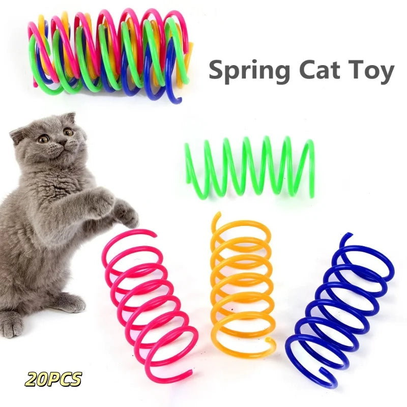 Eine Sammlung farbenfroher Springspielzeuge für Katzen, darunter grüne, blaue und orange Spiralen, neben einem grauen Kätzche