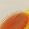 Close-up of an orange pet deshedding brush with numerous fine bristles and a yellow handle.
