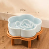 A light blue ceramic cat bowl with a raised rim is displayed on a natural wooden stand.