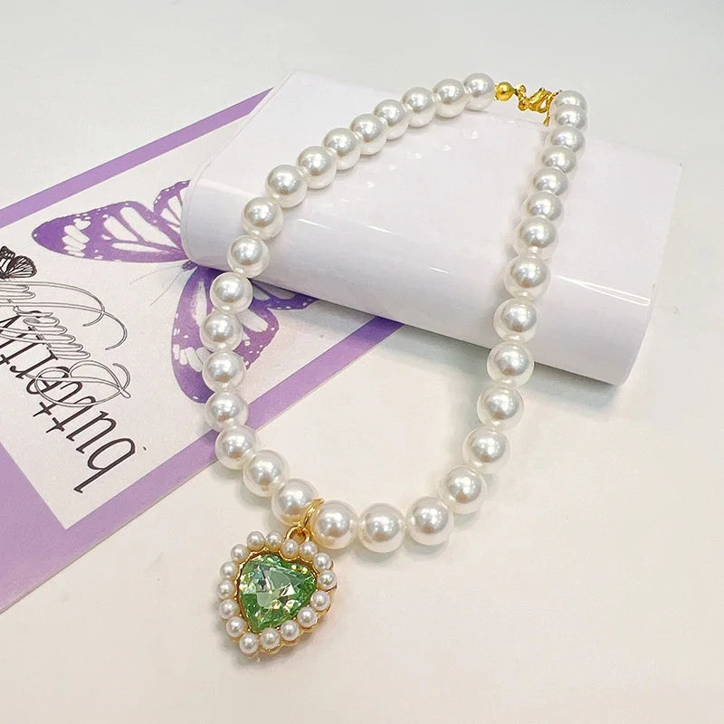 A delicate pearl necklace with a green gemstone pendant displayed on a white box.