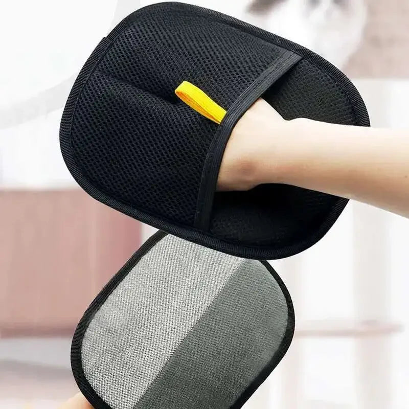 Una mano lleva un guante reutilizable para peluquería de mascotas negro con un dedo de acento amarillo.