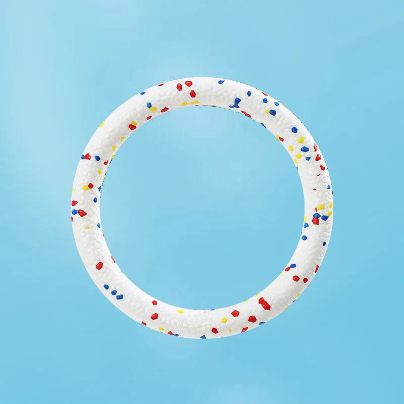 A white, ring-shaped chew toy for dogs, decorated with small colorful pellets.