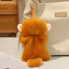 An orange cartoon animal bean bag plush toy with pink ears hanging from a light-colored tote bag.
