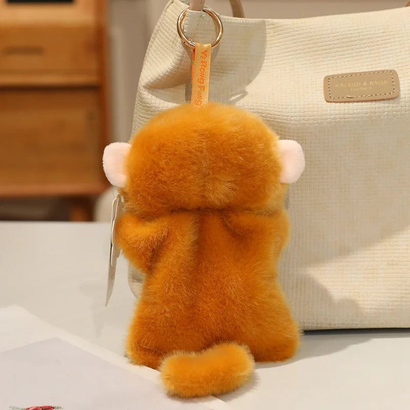 An orange cartoon animal bean bag plush toy with pink ears hanging from a light-colored tote bag.