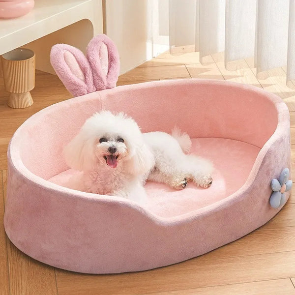 A pink cozy pet bed with a removable cover is shown containing a white fluffy dog.