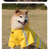 Ein flauschiger Shiba Inu trägt einen gelben, wasserdichten reflektierenden Hunde-Regenmantel im Freien.