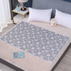 A light blue floral patterned waterproof bed protector pad laid on a beige bed surface.