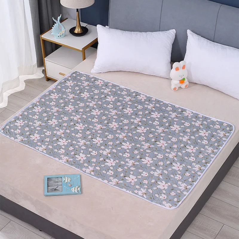 A light blue floral patterned waterproof bed protector pad laid on a beige bed surface.