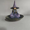 A resin figurine of a witch with a pointed hat and long hair sitting in a bowl.
