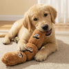 A golden retriever puppy lies on a rug next to a brown plush sausage dog chew toy.