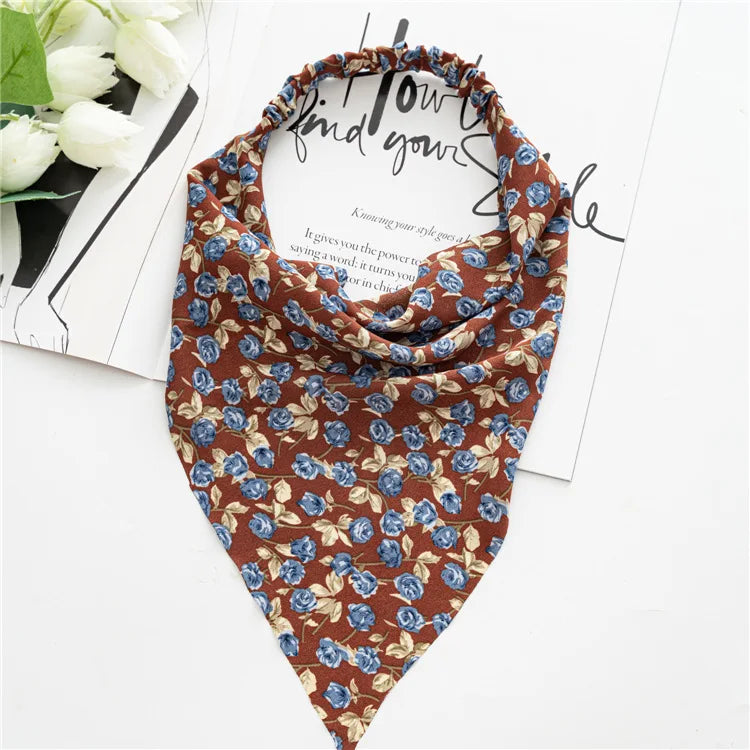 A brown and blue floral paisley triangle scarf tied around the neck, displayed on white paper.